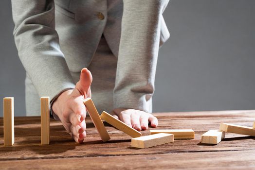 Business woman hand block domino effect. Business risk management and stabilisation situation. Life insurance company presentation with wooden blocks on table. Protection from economic crisis.