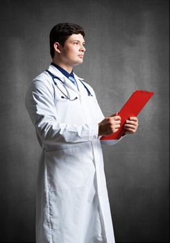 Doctor with tablet for documents, scans documents against the background of the wall