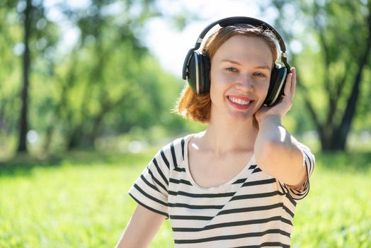 Young attractive woman listens to music in the park. Enjoying music in the park