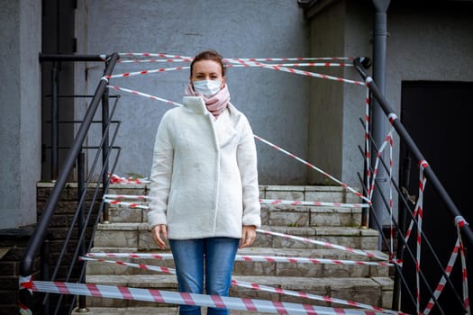 Photo of a girl in a mask. Standing on the street with danger warning tapes. isolated Covid-19 pandemic.