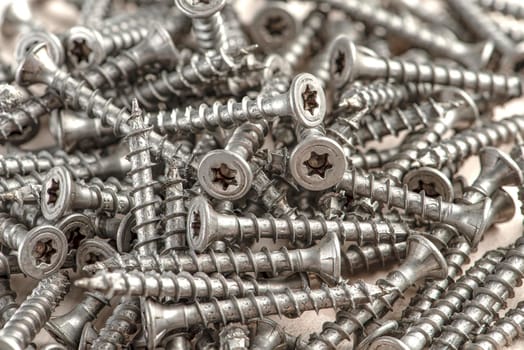 Close-up of universal silver screws with torx head. Self-tapping screws for wood, plywood or chipboard. Torx screws close up