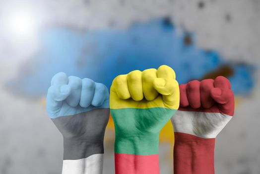 The Baltic countries support Ukraine. Humanitarian aid to Ukraine. The fist is painted in the colors of the flag of Lithuania, Latvia, Estonia against the background of the Ukrainian flag