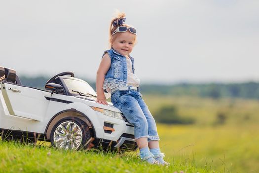 girl in sunglasses stands near the car in nature