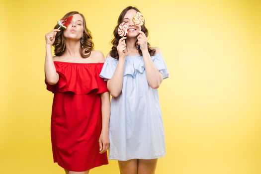 Horizontal portrait of two cheerful young women having fun together on background.