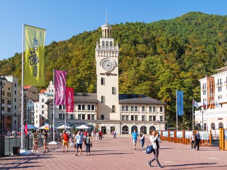 SOCHI, RUSSIA - October 13, 2018. Tourist walk near clock tower on Rosa square in Rosa Dolina. Famous Rosa Khutor Alpine Ski Resort near Sochi.