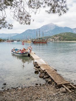 PHASELIS, TURKEY - May 19, 2018. Tourists get into the boat after excursion. Touristic yachts and boats in harbour of ancient ruins of Phaselis city.