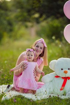 mother and daughter in pink dresses and with pink balloons in nature