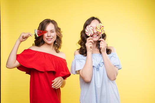 Horizontal portrait of two cheerful young women having fun together on background.