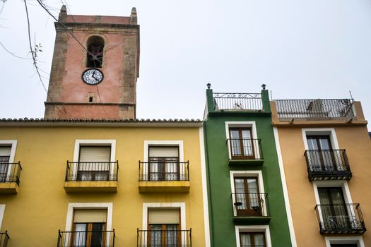 Colorful facades in Villajoyosa town. Bell tower of Asuncion Virgin Church in the background.