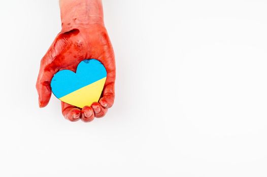 Woman with hands covered in blood holding a heart with the flag of ukraine on a white background. Copy spae
