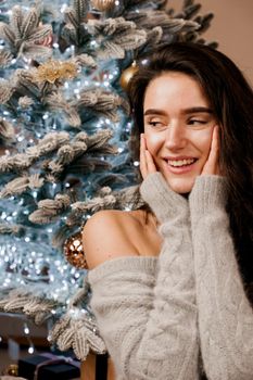 Girl near the Christmas tree smiling and posing. Seasonal advertising before the new year. Celebrating christmas at home