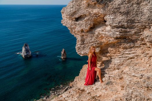 A woman in a red flying dress fluttering in the wind, against the backdrop of the sea