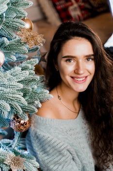 Portrait of a girl near the Christmas tree close-up. New Year celebration. Waiting for gifts.