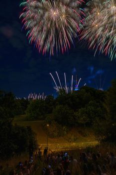 Colorful fireworks with people looking and the Munich Olympic Tower in the background, Munich, Germany.