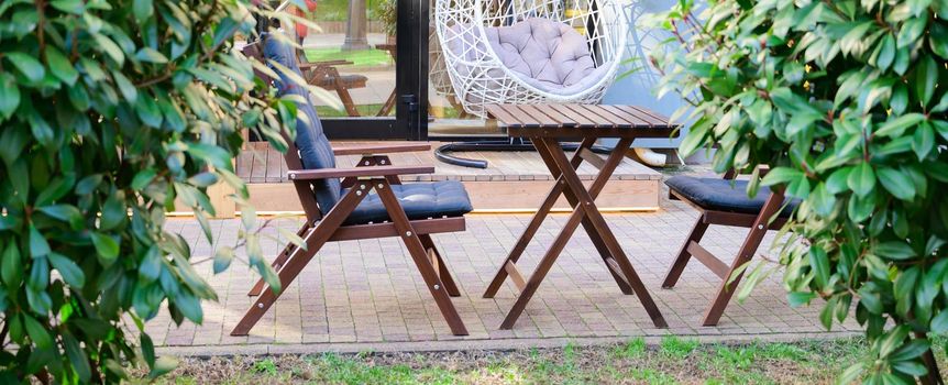 Summer veranda Cafe with simple wooden furniture and a hanging wicker chair