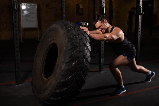 Caucasian man pushing a car tire in the gym