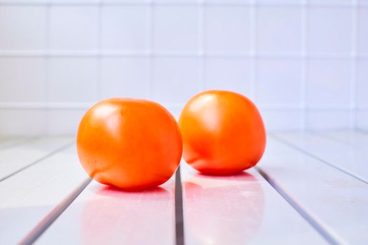 a glossy red, or occasionally yellow, pulpy edible fruit that is eaten as a vegetable or in salad.Two tomatoes on a striped table with a checkered back.