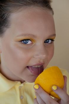 charming tween girl with slices of ripe lemon on yellow background. juicy fruit concept. summer.