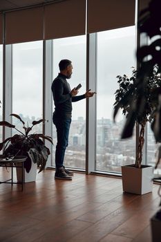 Adult man standing near big window in office space