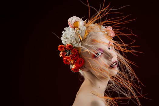 A girl with lively curly hair and flowers in her head. Art object. Flower girl fairy