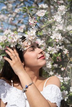 Spring concept. Nature.Young caucasian woman enjoying the flowering of an apple trees, walking in spring apple gardens