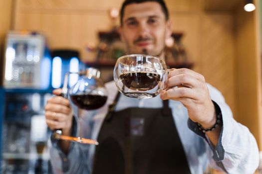 Syphon alternative method of making coffee. Barista gives hot coffee in double glass cup to customers. Coffee brewing in cafe