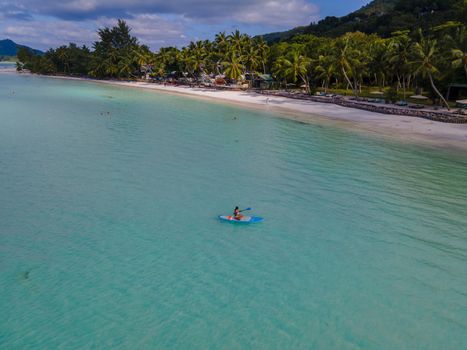 woman with paddleboard sup in ocean, Praslin Seychelles tropical island with withe beaches and palm trees, the beach of Anse Volbert Seychelles.