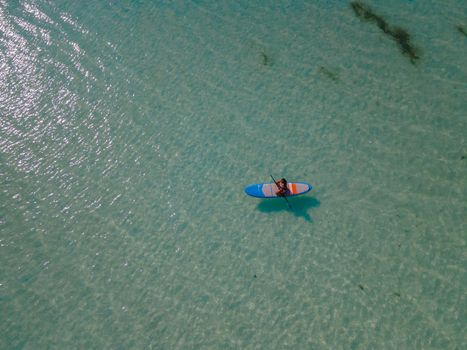 woman with paddleboard sup in ocean, Praslin Seychelles tropical island with withe beaches and palm trees, the beach of Anse Volbert Seychelles.