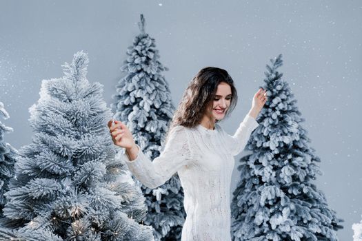 New year celebration. Attractive girl with falling snow . Young woman weared in a warm white pullover and white socks