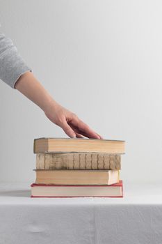 Stack of old rustic vintage books with the hand on white table