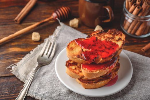 Stack of french toasts with berry marmalade on white plate