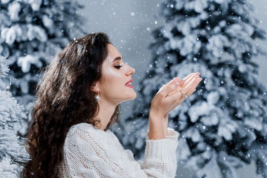 New year celebration. Attractive girl close-up with falling snow . Young woman weared in a warm white pullover and white socks