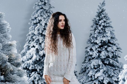 New year celebration.Happy girl with falling snow. Young woman weared in a warm white pullover and white socks. Winter holidays in snowy day