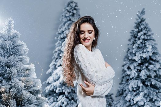 New year celebration. Attractive girl with falling snow . Young woman weared in a warm white pullover and white socks