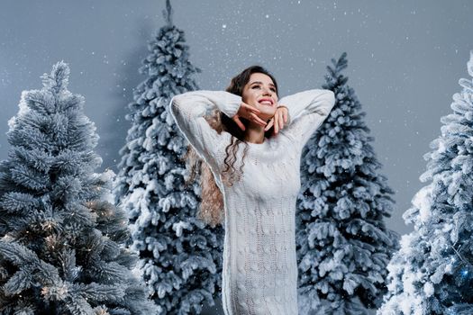 New year celebration. Attractive girl with falling snow . Young woman weared in a warm white pullover and white socks