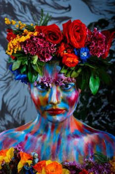 Portrait of a girl whose face is painted with colored paints in a wreath of flowers. In Frida Kahlo's footsteps.