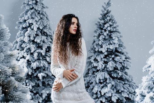 New year celebration.Happy girl with falling snow. Young woman weared in a warm white pullover and white socks. Winter holidays in snowy day