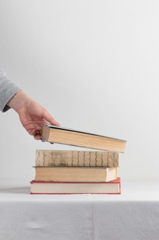 Stack of old rustic vintage books with the hand on white table