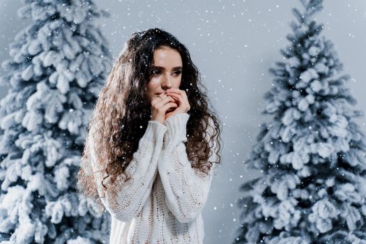 New year celebration.Happy girl with falling snow. Young woman weared in a warm white pullover and white socks. Winter holidays in snowy day