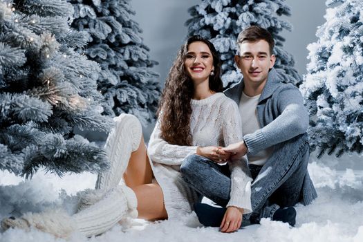 New year love story. Couple kiss and hug. Happy young couple near christmas trees in winter day.