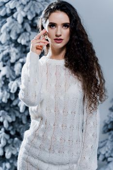 New year celebration.Happy girl with falling snow. Young woman weared in a warm white pullover and white socks. Winter holidays in snowy day