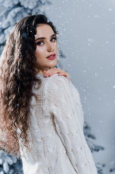 New year celebration.Happy girl with falling snow. Young woman weared in a warm white pullover and white socks. Winter holidays in snowy day