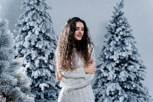 New year celebration.Happy girl with falling snow. Young woman weared in a warm white pullover and white socks. Winter holidays in snowy day