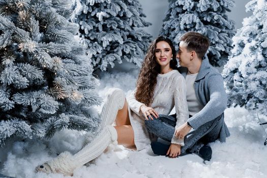 New year love story. Couple kiss and hug. Happy young couple near christmas trees in winter day.