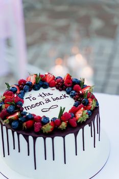 Wedding cake with strawberries and blueberries on top. White tasty cake for ceremony. Advert for cooks.