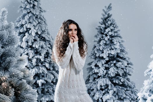 New year celebration.Happy girl with falling snow. Young woman weared in a warm white pullover and white socks. Winter holidays in snowy day