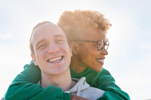 portrait of a young couple of latin woman and caucasian man smiling happy at sunset, concept of friendship and couple relationship