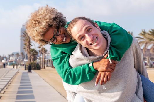 portrait of a happy young couple laughing and having fun with the woman piggybacked by her boyfriend, concept of friendship and fun in a relationship