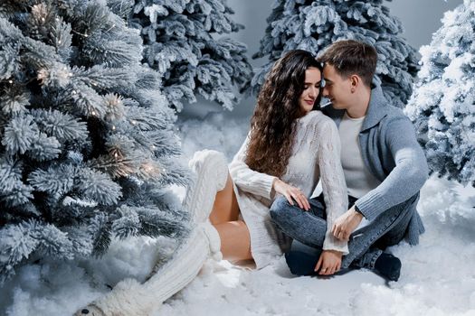 New year love story. Couple kiss and hug. Happy young couple near christmas trees in winter day.