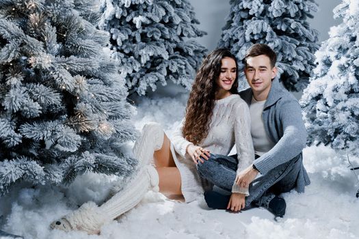 New year love story. Couple kiss and hug. Happy young couple near christmas trees in winter day.